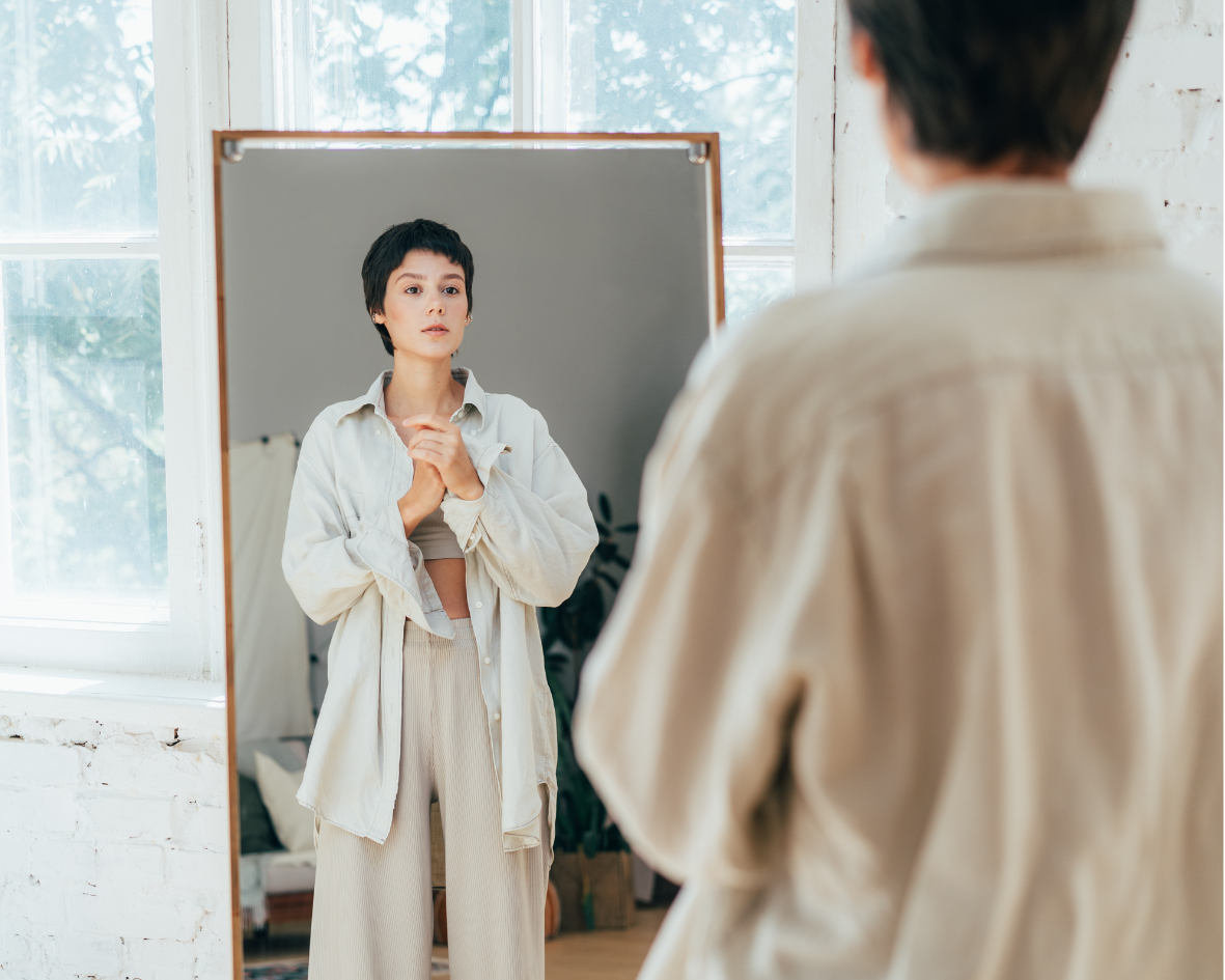 Woman looking at her reflection in a mirror, exploring self-awareness and inner connection.