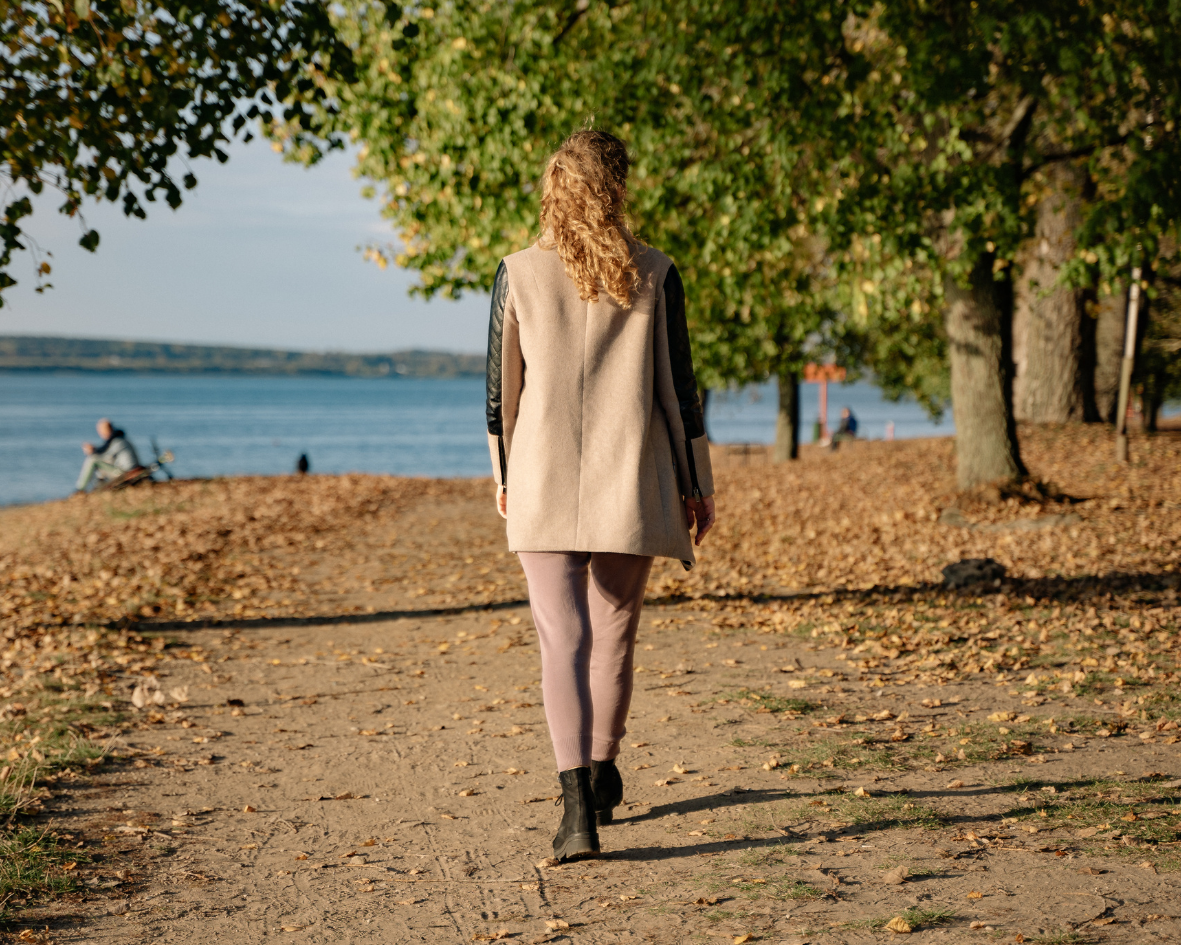 Person walking alone on a lakeside path, illustrating solitude and the journey to reconnect with oneself.