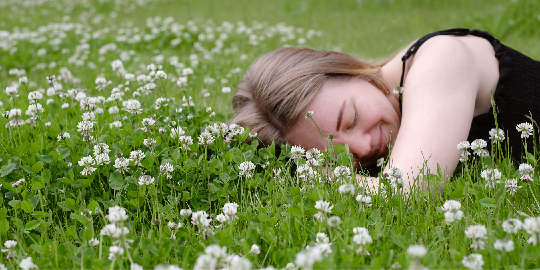 Young woman peacefully resting between wild flowers